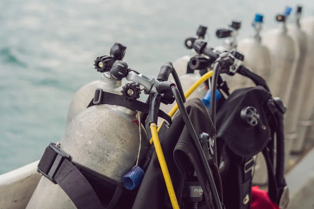 Row of yellow and silver aluminum scuba cylinders secured in tank racks aboard a dive boat