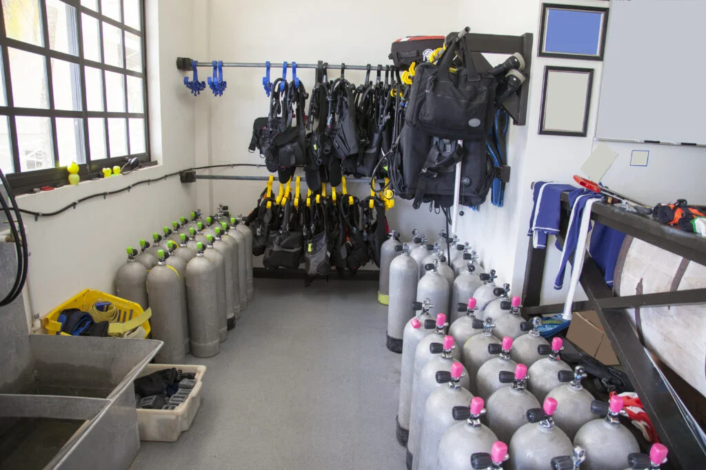 Scuba diver rinsing regulator first stage and BCD with fresh water during post-dive gear maintenance