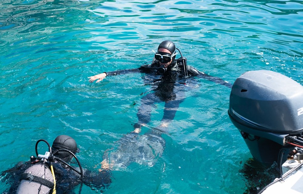 PADI scuba instructor assisting a student diver with buoyancy adjustment during open water training
