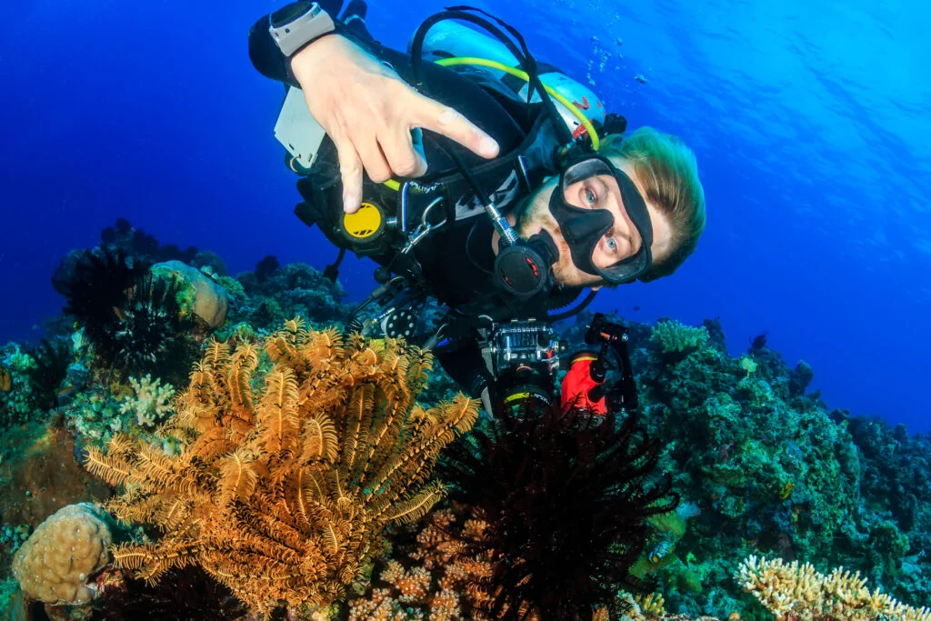 Scuba diver swimming along a vibrant tropical coral reef during open water training