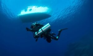 Technical diver equipped with manifold double cylinders and deco stage bottles preparing for mixed gas dive